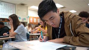 student writing notes at desk 